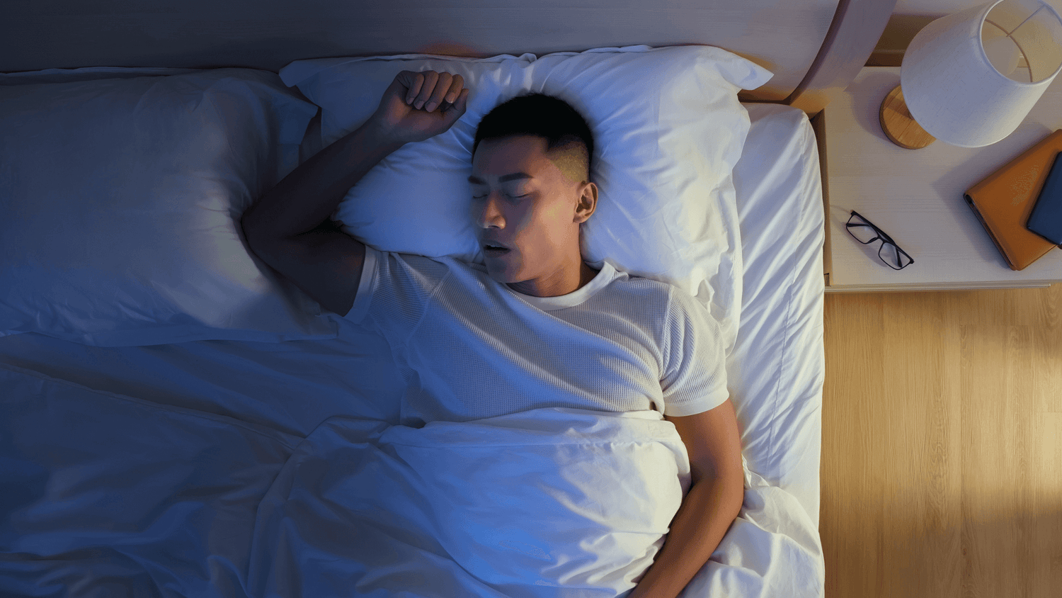 Top view of man sleeping in bed with his mouth open snoring.