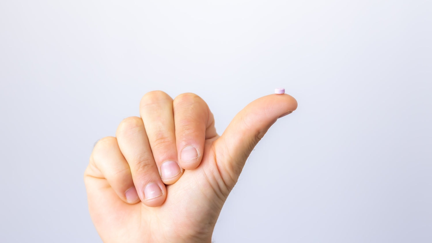 Close up picture of a hand making a thumbs-up gesture. There is a MyoSpot balancing on the thumb.